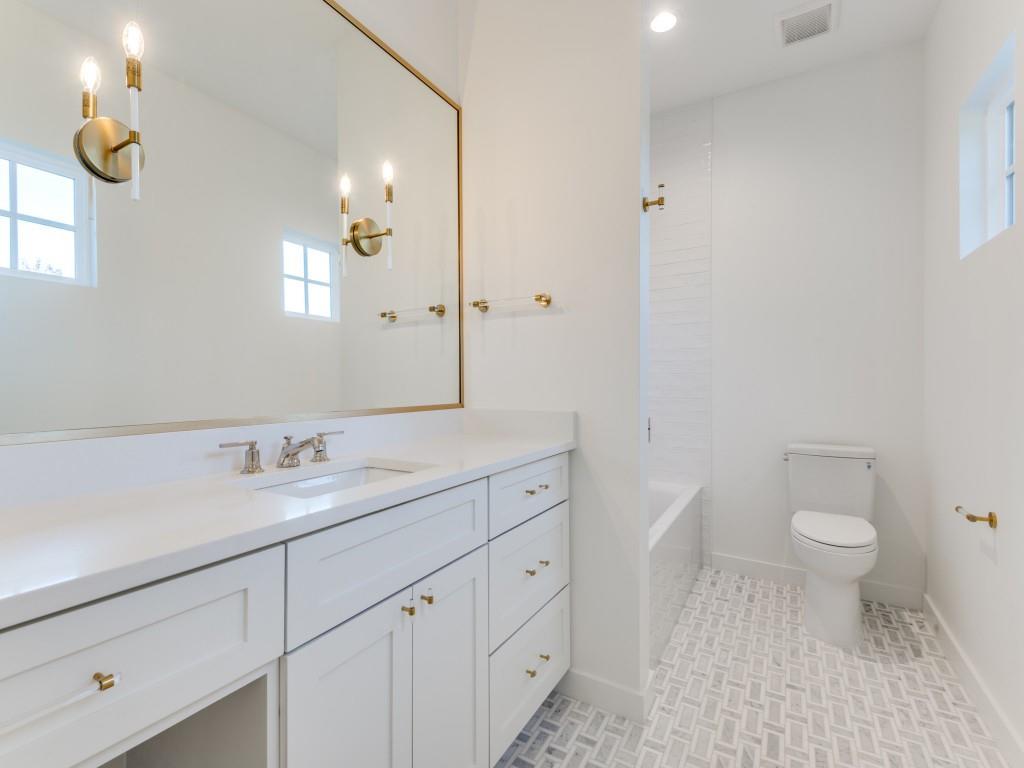 3838 Princess Lane Dallas, TX 75229 - Photo 21 of 26 a bathroom with a toilet a sink a light fixture and a window
