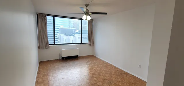 an empty room with chandelier fan and windows