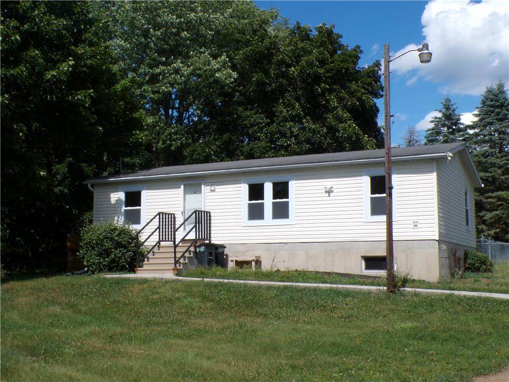 A modest home with vinyl siding and concrete foundation, nestled amidst lush trees, offers a tranquil setting.