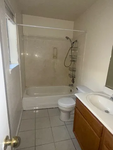 a bathroom with a granite countertop bathtub shower sink vanity and toilet