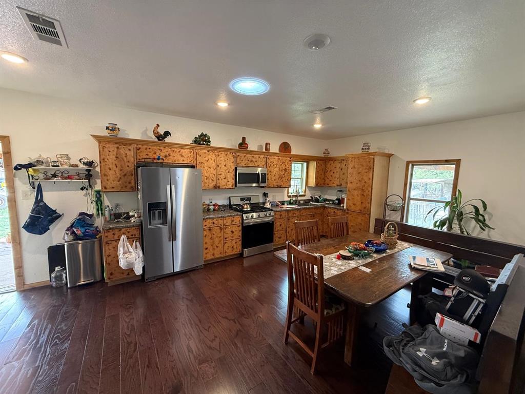 900 North Tiffin Road Ranger, TX 76470 - Photo 13 of 33 a kitchen with stainless steel appliances granite countertop a refrigerator a stove top oven a sink dishwasher and a dining table with wooden floor