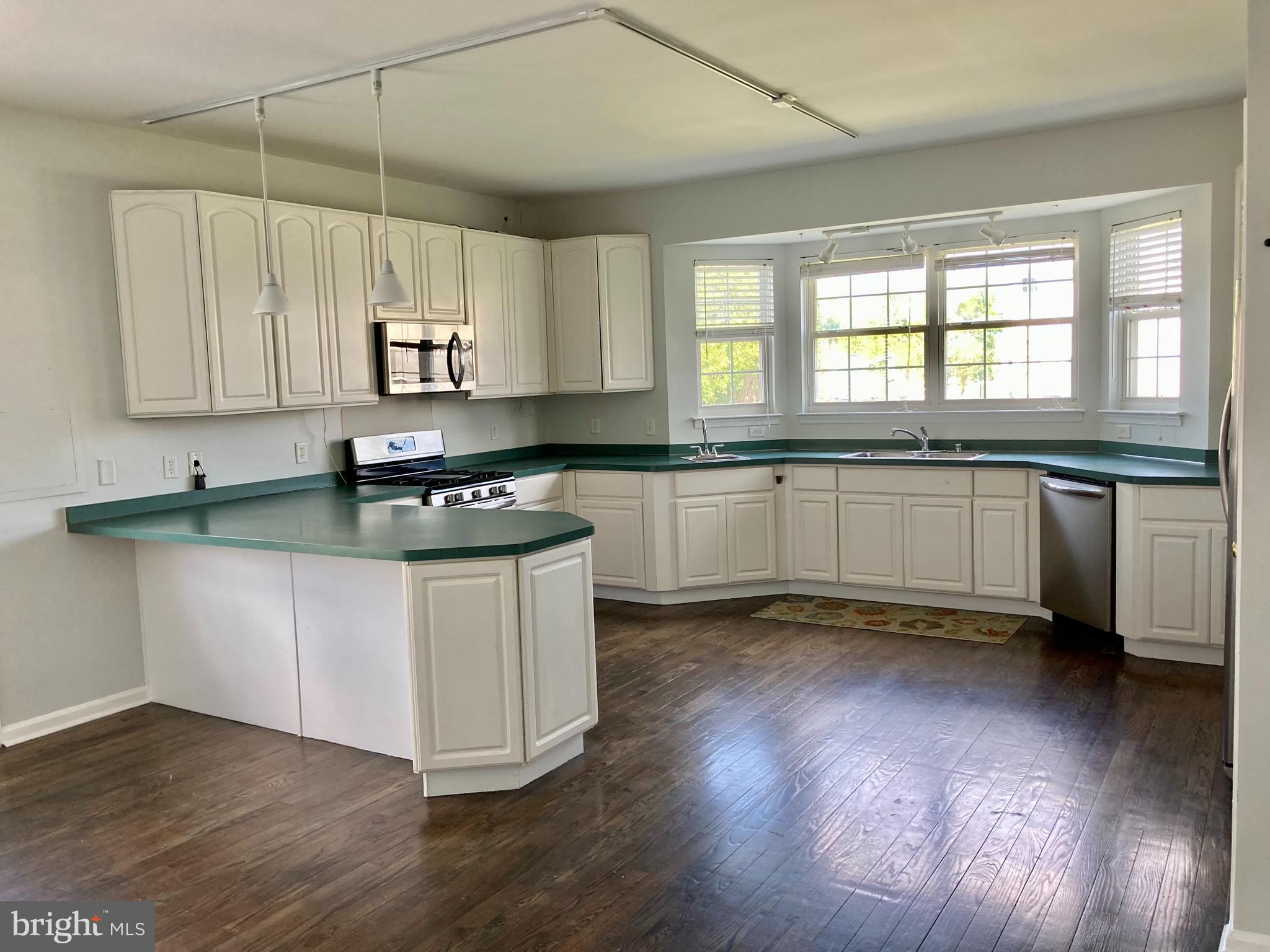 227 Mariners Way Bear, DE 19701 - Photo 6 of 19 a kitchen with granite countertop a stove a sink and white cabinets with wooden floor