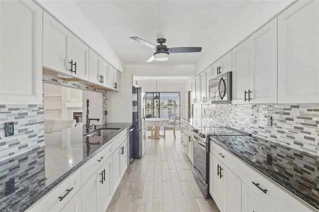 a kitchen with stainless steel appliances granite countertop a sink stove cabinets and refrigerator