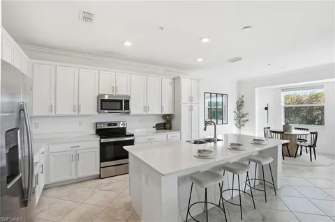 a kitchen with stainless steel appliances kitchen island granite countertop a stove a sink a dining table and chairs