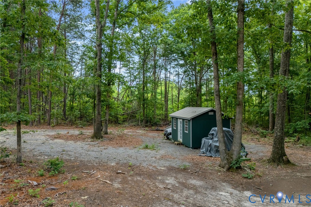 a view of a barn in the middle of a forest