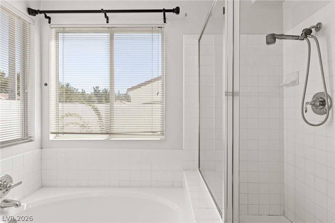 1815 Stablegate Avenue Henderson, NV 89012 - Photo 20 of 28 A well-lit primary bath features a spacious soaking tub alongside a sleek, glass-enclosed shower.