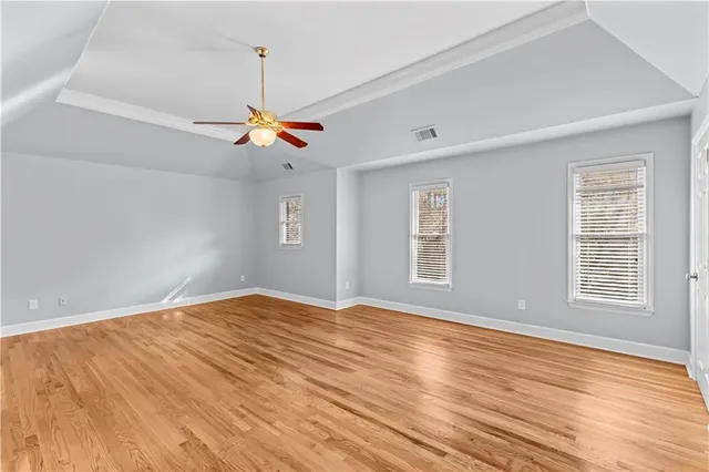a view of empty room with wooden floor and fan