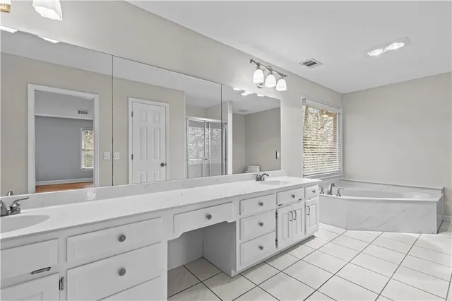 a spacious bathroom with a double vanity sink mirror and bathtub