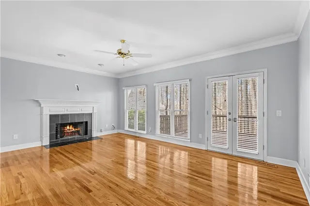 a view of an empty room with wooden floor fireplace and a window