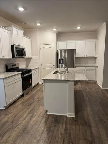 a kitchen with stainless steel appliances granite countertop a sink a stove a refrigerator and cabinets