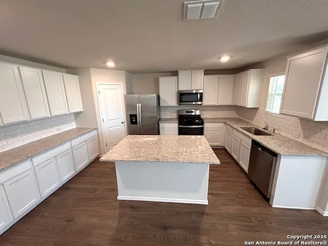 a large kitchen with cabinets wooden floor and stainless steel appliances