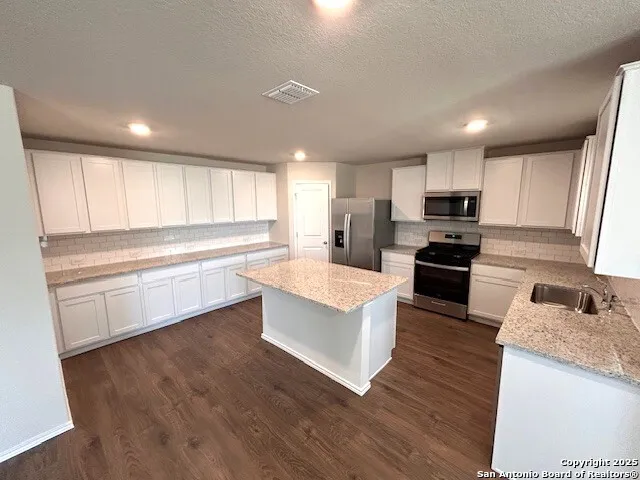 a large kitchen with cabinets wooden floor and stainless steel appliances