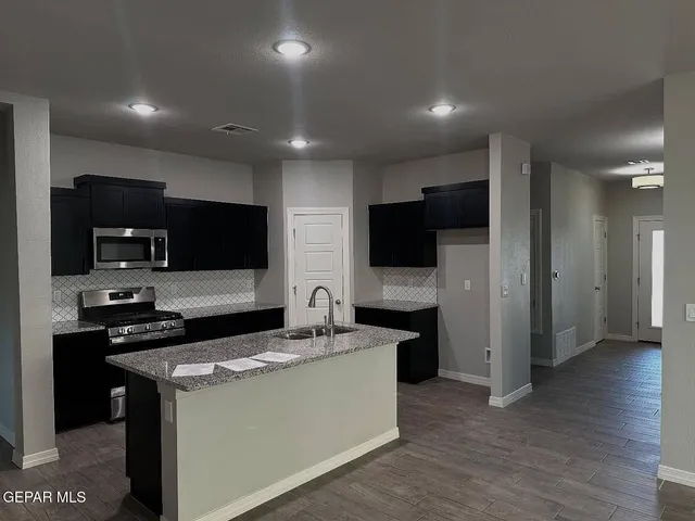 a kitchen with a sink stainless steel appliances a refrigerator and cabinets