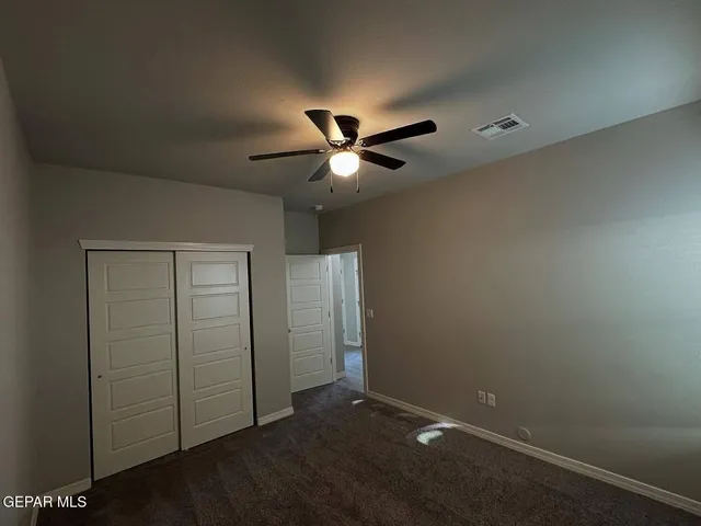 an empty room with closet and ceiling fan