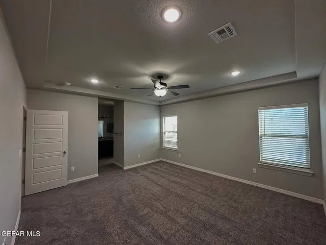 en empty room with windows and ceiling fan