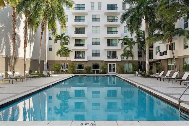 a view of a swimming pool with a lawn chairs and palm trees