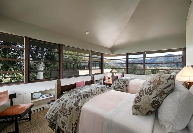 a large bedroom with bed and large windows