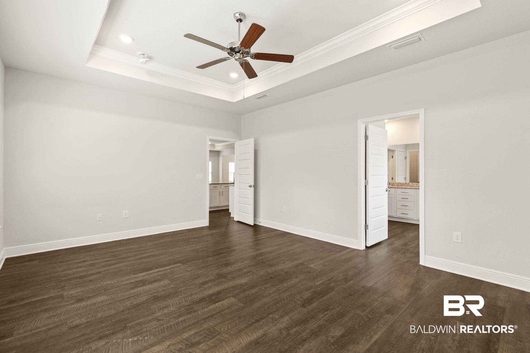 9448 Amethyst Drive Daphne, AL 36526 - Photo 25 of 61 Unfurnished bedroom with dark wood-style flooring, ceiling fan, crown molding, ensuite bathroom, and a raised ceiling