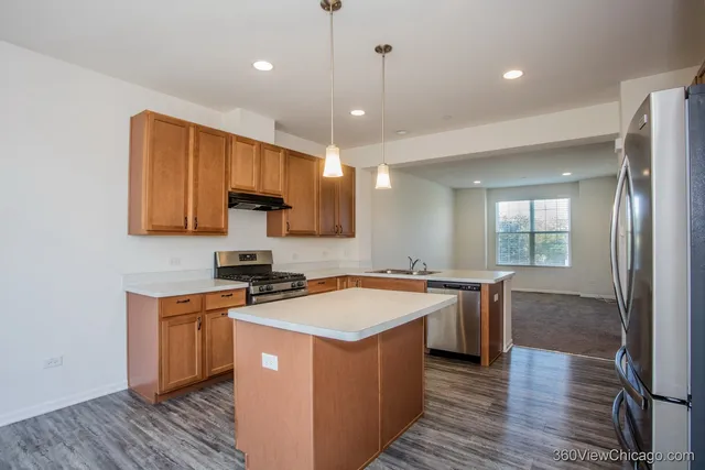 a kitchen with a stove a sink a refrigerator and wooden floor