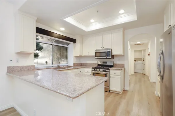 a large kitchen with stainless steel appliances granite countertop a sink a stove and a refrigerator