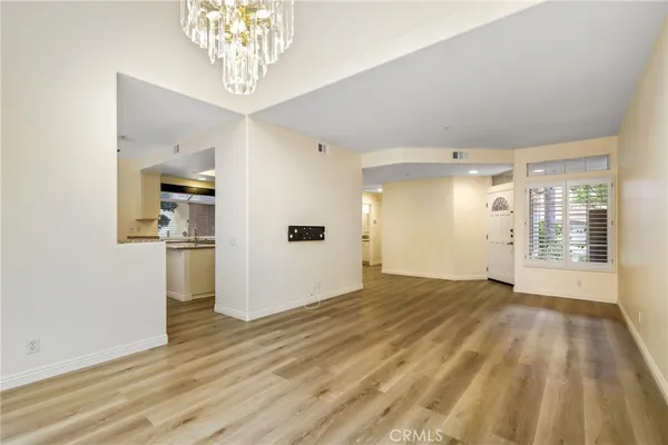 a view of a big room with wooden floor and a kitchen