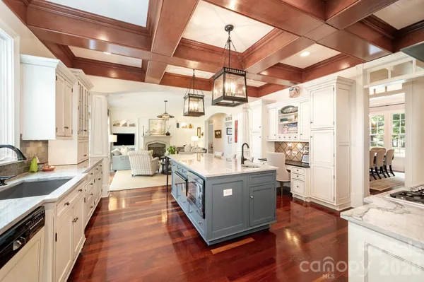 a large kitchen with stainless steel appliances a stove a sink dishwasher and white cabinets with wooden floor