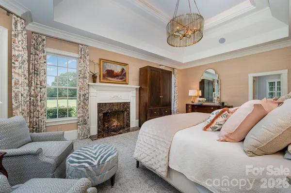 a bedroom with a bed large window and a chandelier