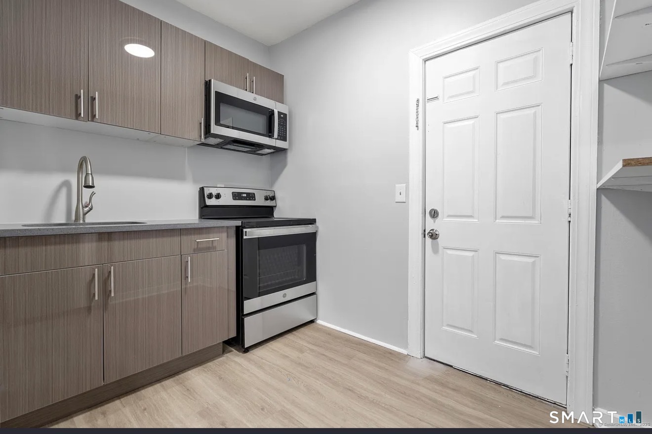 25 Whittier Street, Unit 3 Bridgeport, CT 06605 - Photo 3 of 7 a kitchen with granite countertop white cabinets stainless steel appliances and sink