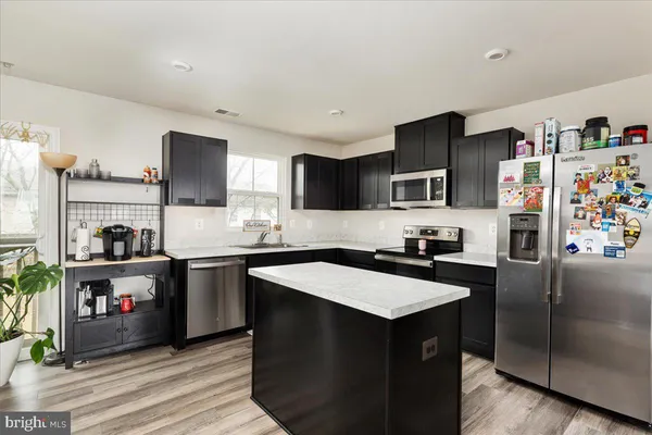 a kitchen with stainless steel appliances granite countertop a refrigerator a sink dishwasher stove and oven with wooden floor