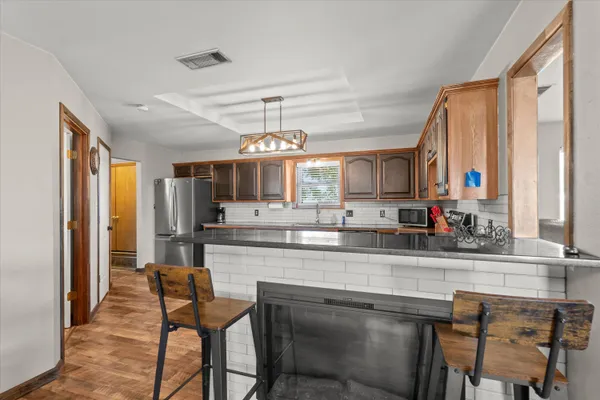a kitchen with stainless steel appliances granite countertop table chairs sink and cabinets