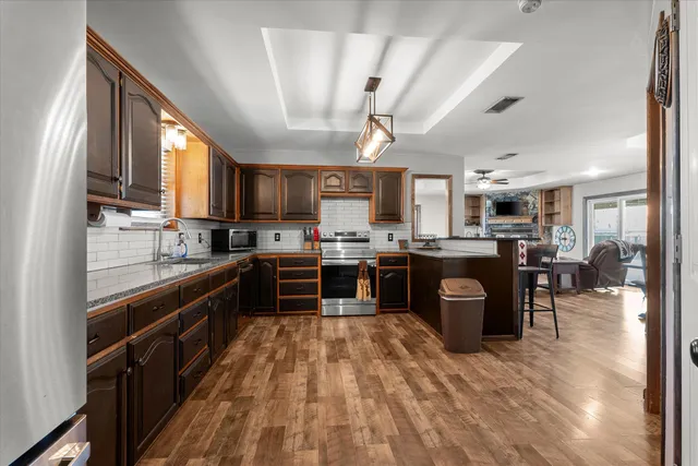 a kitchen with stainless steel appliances kitchen island granite countertop a stove refrigerator a sink dishwasher and a microwave oven with cabinets