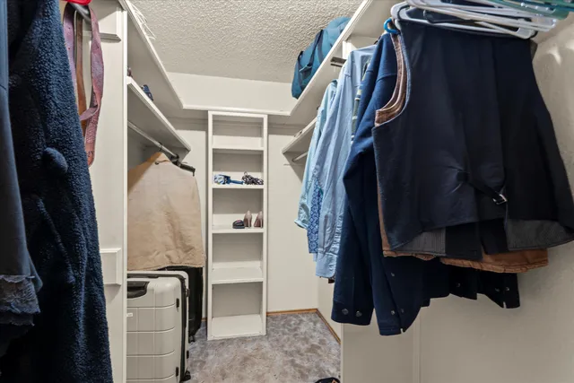 a view of walk in closet with clothes and shoes