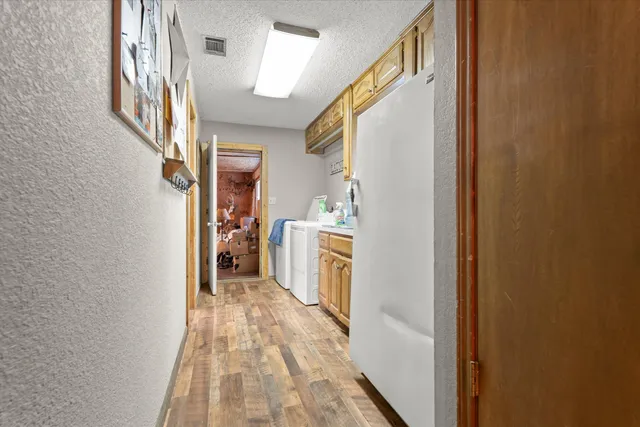 a view of a hallway with wooden floor and washer