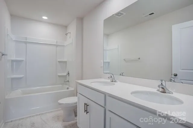 a bathroom with a granite countertop sink a toilet and bathtub