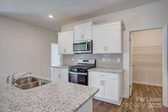 a kitchen with white cabinets sink and stainless steel appliances