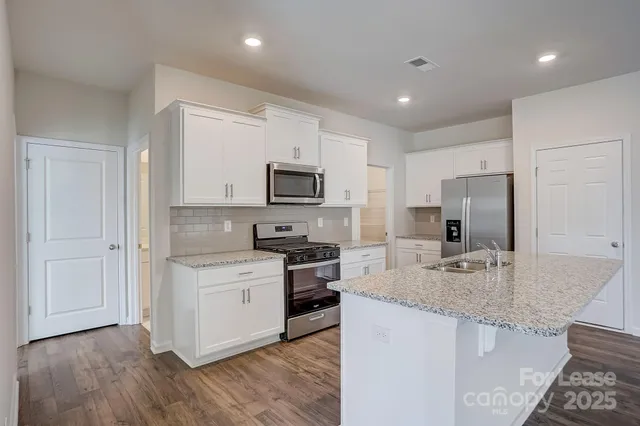 a kitchen with stainless steel appliances granite countertop a stove top oven a sink and a refrigerator