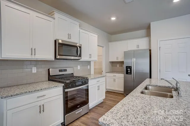 a kitchen with granite countertop a sink stove and refrigerator