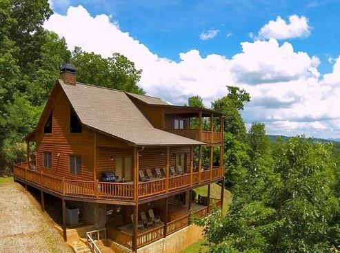 499 Raven Ridge Circle Mineral Bluff, GA 30559 - Photo 1 of 43 a roof deck with table and chairs under an umbrella