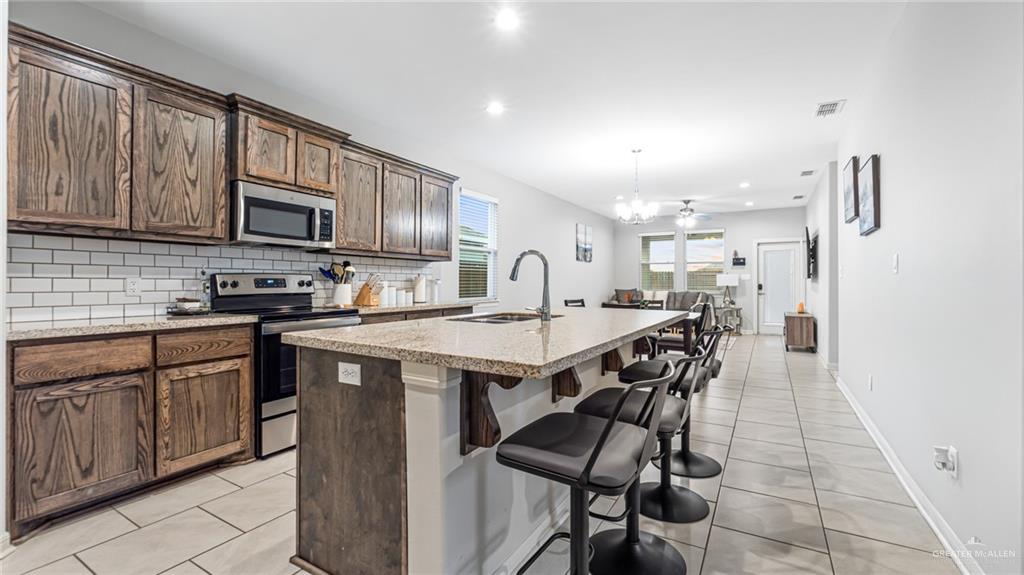 14208 Boykin Creek Road McAllen, TX 78504 - Photo 5 of 30 a kitchen with stainless steel appliances granite countertop a stove a sink dishwasher and a refrigerator with wooden cabinets