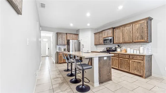 a kitchen with stainless steel appliances granite countertop a stove a sink dishwasher and a refrigerator with wooden cabinets