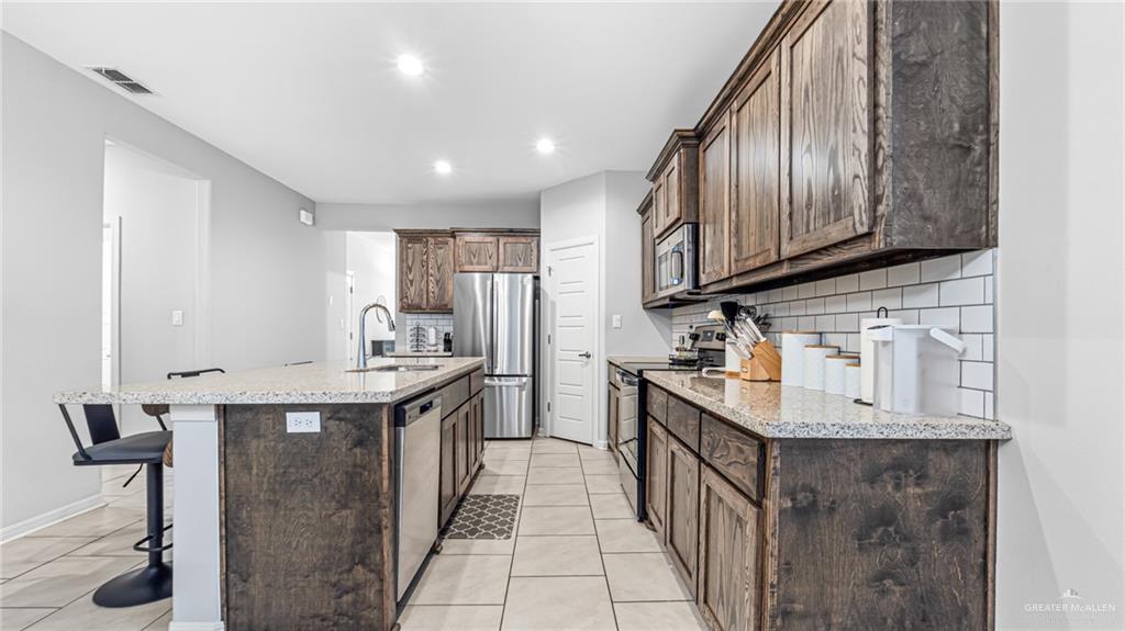 14208 Boykin Creek Road McAllen, TX 78504 - Photo 7 of 30 a kitchen with stainless steel appliances granite countertop a sink a stove and a wooden floors