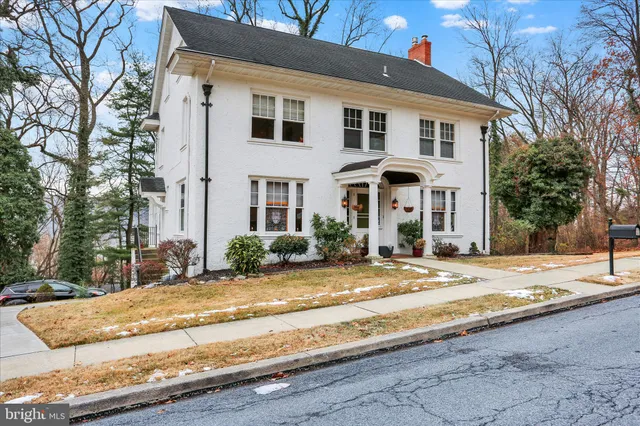 a front view of a house with garden and trees
