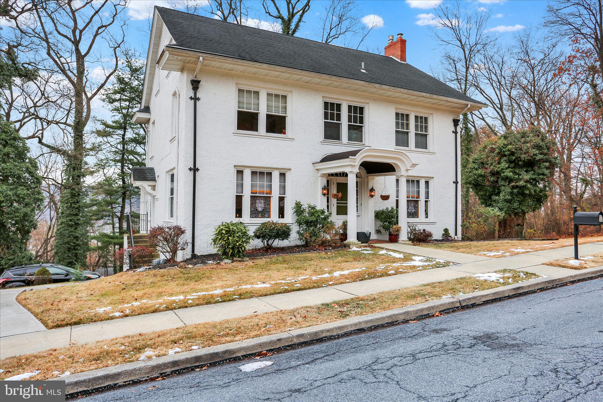 a front view of a house with garden and trees