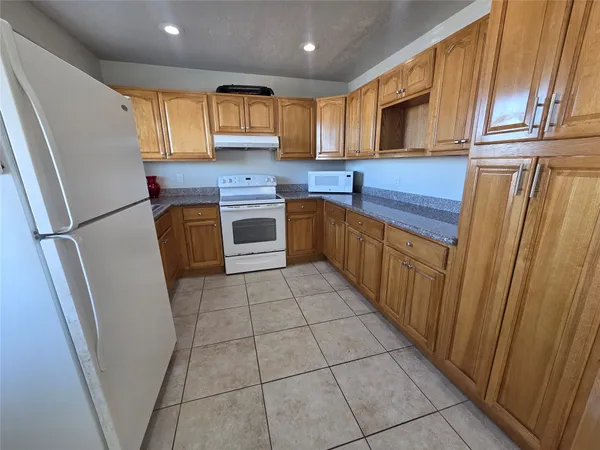 a kitchen with stainless steel appliances granite countertop a refrigerator a sink a stove a microwave oven and cabinets