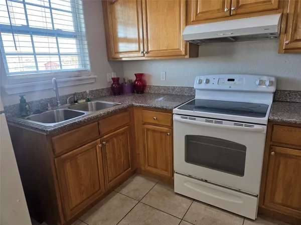 a kitchen with granite countertop a sink a stove and cabinets