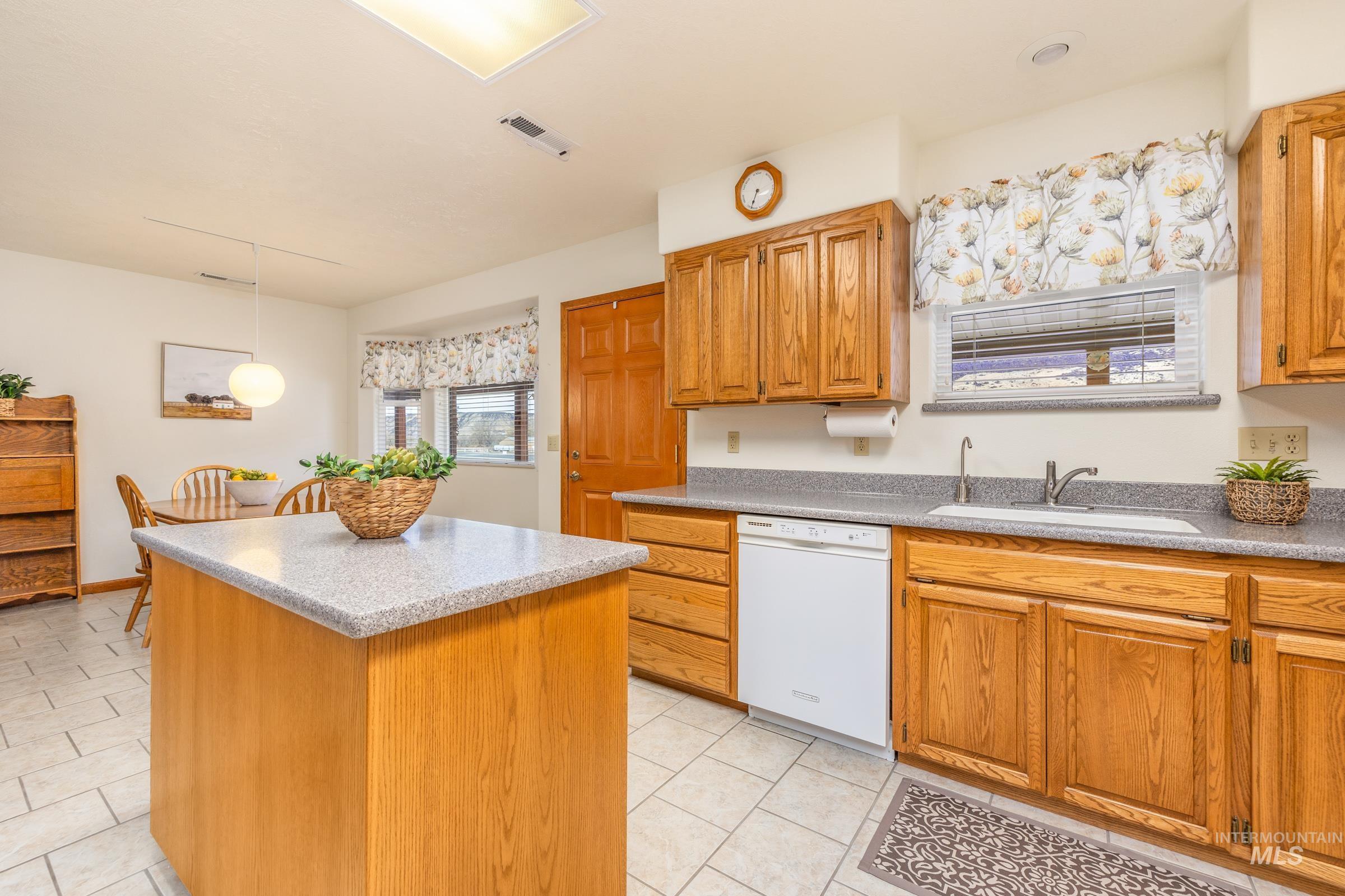 10514 Airpark Loop Road Melba, ID 83641 - Photo 17 of 48 Kitchen with a center island, wood finish cabinets, dishwasher, light tile patterned flooring, and hanging light fixtures