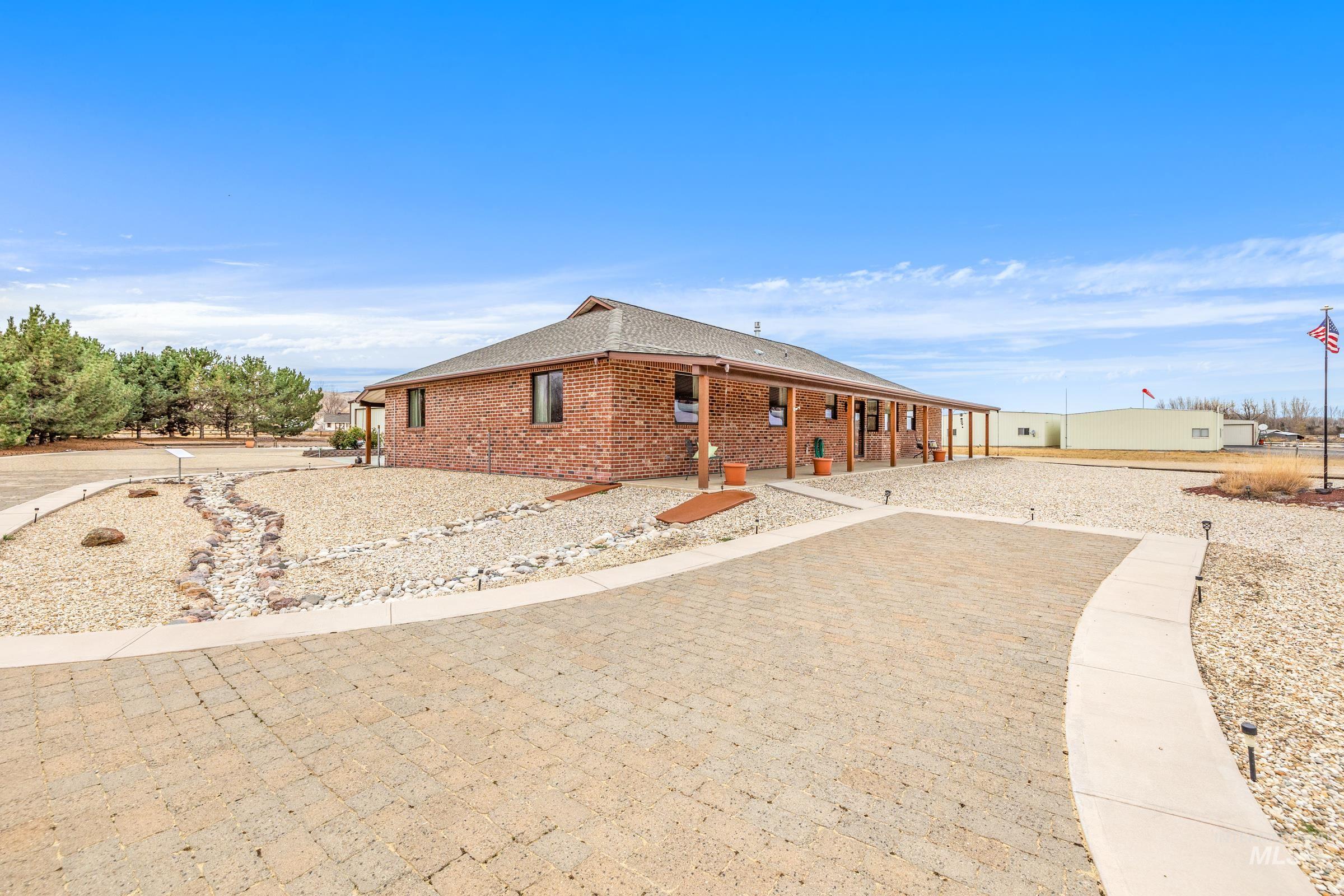 10514 Airpark Loop Road Melba, ID 83641 - Photo 29 of 48 View of property exterior with a shingled roof, brick siding, and a porch