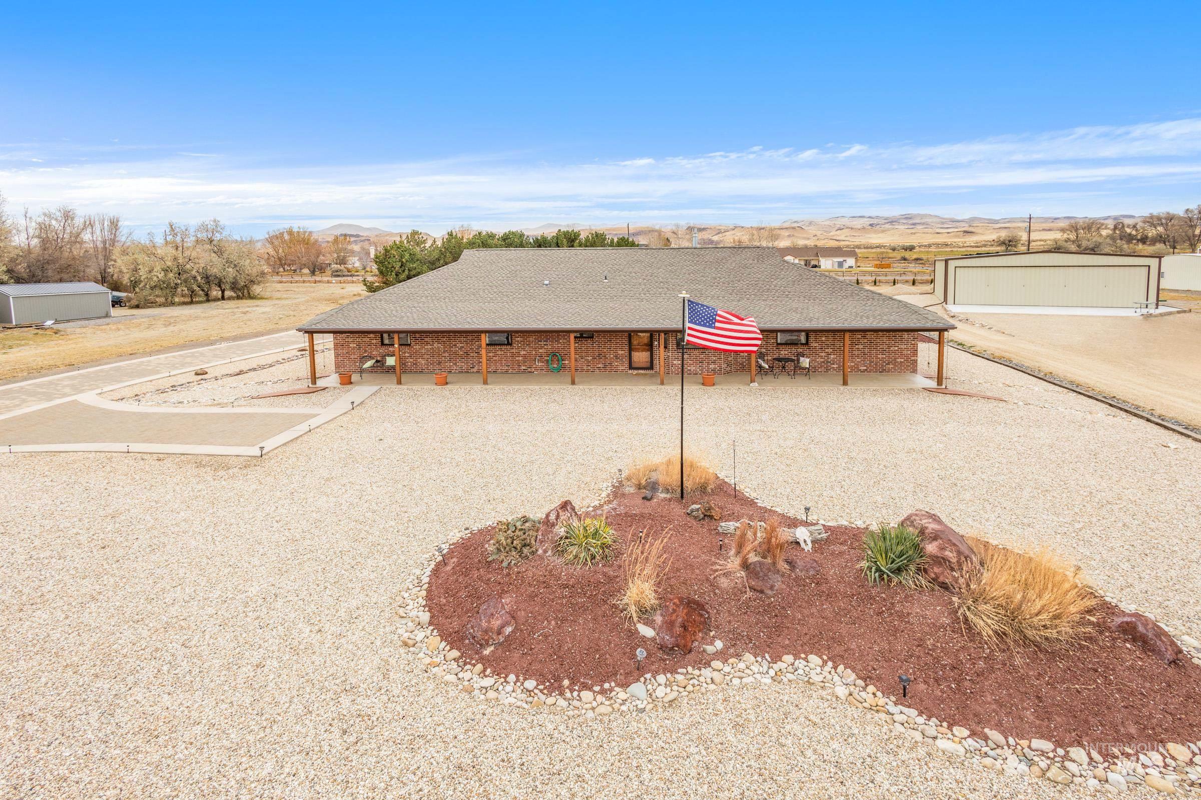 10514 Airpark Loop Road Melba, ID 83641 - Photo 3 of 48 View of front facade featuring a shingled roof, brick siding, a mountain view, and a patio area