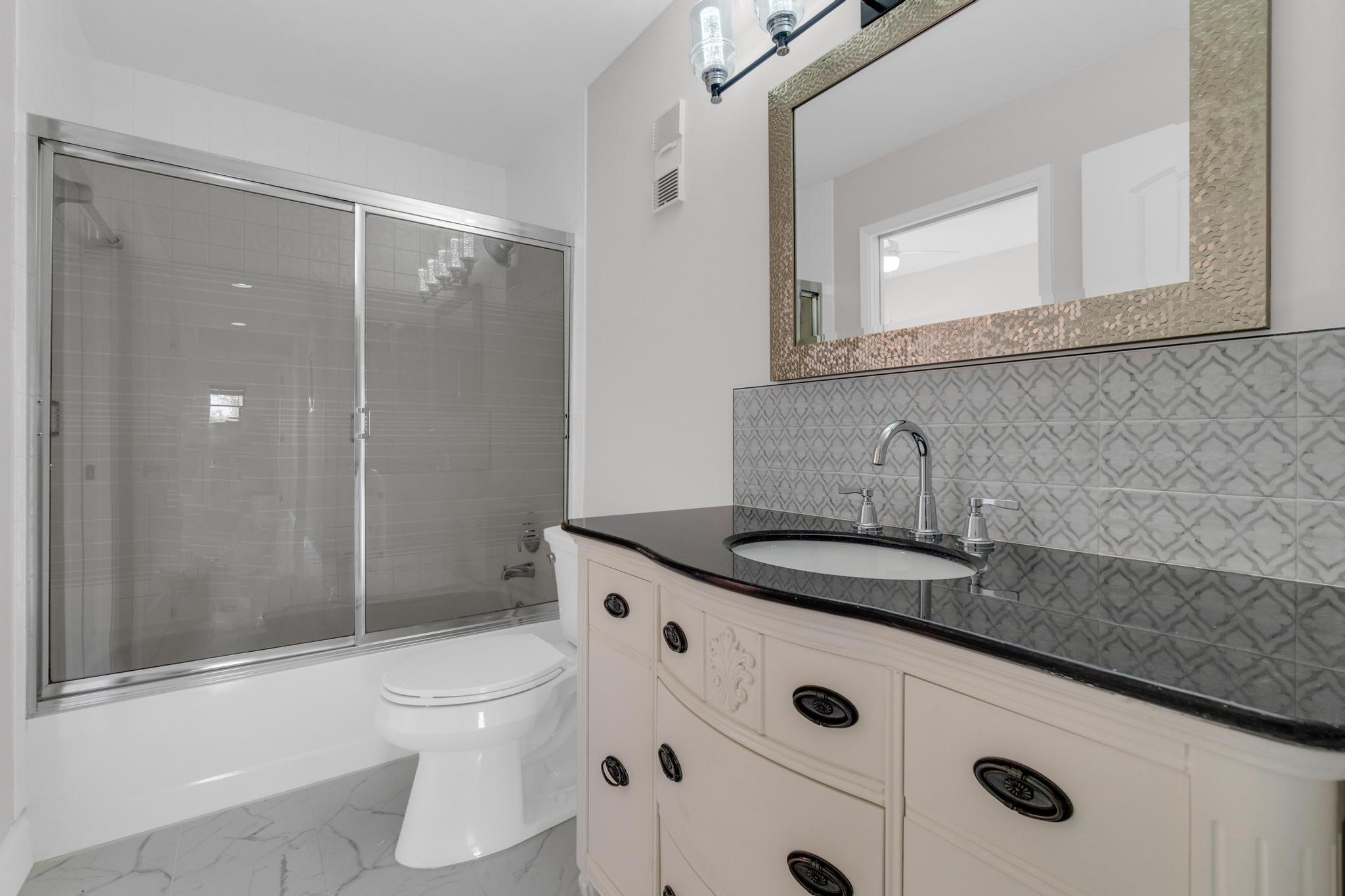 6241 Pointe Regal Circle, Unit 402 Delray Beach, FL 33484 - Photo 13 of 23 a bathroom with a granite countertop sink a toilet a mirror and shower