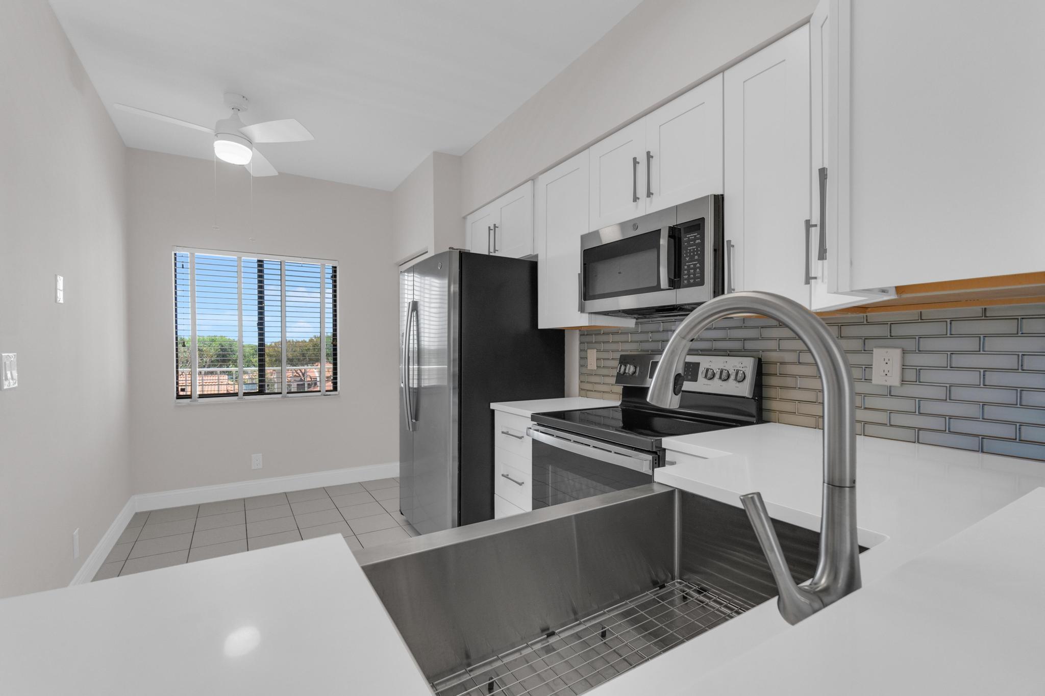6241 Pointe Regal Circle, Unit 402 Delray Beach, FL 33484 - Photo 2 of 23 a kitchen with stainless steel appliances a refrigerator a stove a microwave and sink